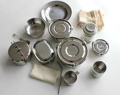 a table topped with lots of metal pots and pans next to utensils