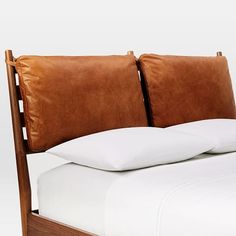 a bed with white sheets and brown leather headboard, made in the style of a wooden frame