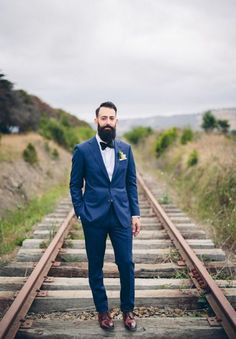 a man in a blue suit standing on train tracks