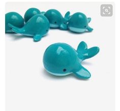 several small plastic blue whale figurines sitting next to each other on a white surface