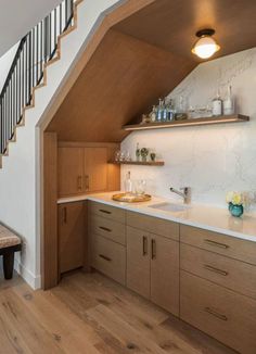 a kitchen with wooden cabinets and white counter tops next to a staircase leading up to the second floor