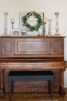 a grand piano with a wreath on top and candles in the corner next to it