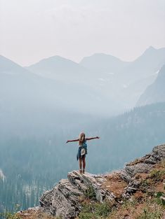 a woman standing on top of a mountain with her arms outstretched