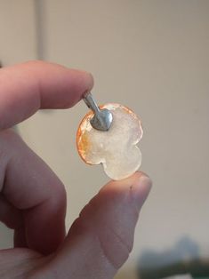 a person is holding an orange and white piece of glass with a metal hook in it