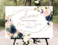 a welcome sign with flowers and greenery on it