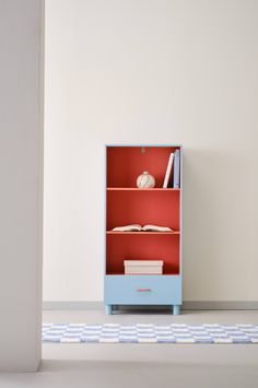 a blue book shelf with books on top and a red book case in the middle