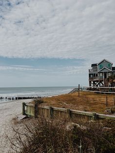 a house sitting on top of a sandy beach next to the ocean