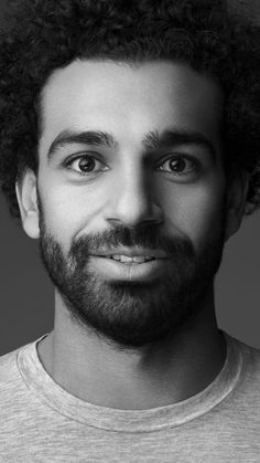 a black and white photo of a man with curly hair wearing a t - shirt