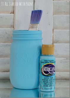 a blue mason jar with a toothbrush in it next to a painted mason jar