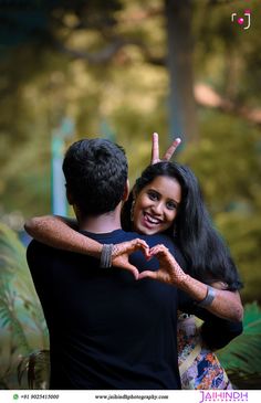 a man and woman making a heart with their hands