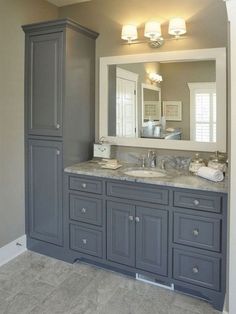 a large bathroom with gray cabinets and marble counter tops, along with two mirrors on the wall