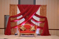 a red chair sitting on top of a white bed covered in curtains and drapes