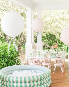 an inflatable pool is set up outside on the porch with balloons and streamers