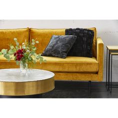 a living room with a couch, table and flowers on the coffee table in front of it