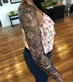 a woman with a tattoo on her arm and leg is standing in a room full of wood floors