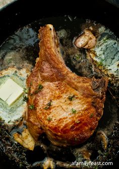 a piece of meat in a skillet with butter and herbs on the side next to some mushrooms