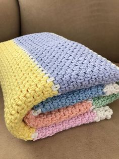 three crocheted blankets stacked on top of each other in different colors and sizes