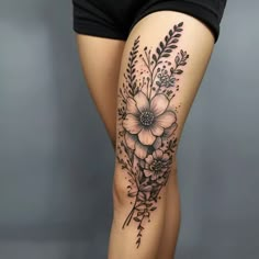 a woman's thigh with flowers and leaves on it