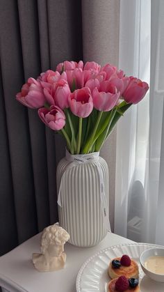 pink tulips in a white vase and pastries on a table