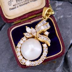 This exquisite pendant is accented with one (1), post set, cultured saltwater pearl, seventeen (17), prong set, round brilliant cut diamonds, three (3), prong set, marquise brilliant cut diamonds and twenty (20), channel/prong set, baguette cut diamonds. The pendant measures 41.7mm X 20.5mm. We have added an 18 inch long 14k yellow gold rounded box chain weighing approximately 3 grams. Formal Pear-shaped Diamond Pearl Necklace, Oval Diamond Jewelry With Pearl Pendant, Elegant Marquise Pearl Drop Jewelry, Evening Pear-shaped Pearl Pendant Jewelry, Diamond Pearl Necklace With Brilliant Cut As A Gift, Brilliant Cut Diamond Pearl Necklace As Gift, Diamond Pendant Pearl Necklace For Anniversary, Brilliant Cut Diamond Pearl Necklace For Gift, Pear-shaped Diamond Jewelry With Pearl Pendant