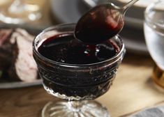 a spoon full of liquid sitting on top of a glass bowl