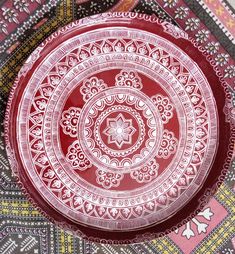 a red and white plate sitting on top of a table covered in patterned cloths