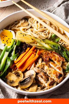 a bowl filled with noodles, carrots, mushrooms and other vegetables next to chopsticks