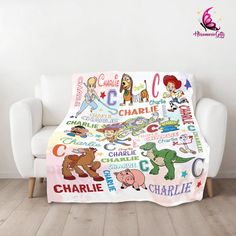 a blanket with cartoon characters on it sitting in front of a white couch and wooden floor