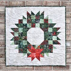 a quilted christmas wreath hanging on a brick wall