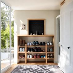 a wooden shelf filled with lots of shoes next to a white door and glass doors