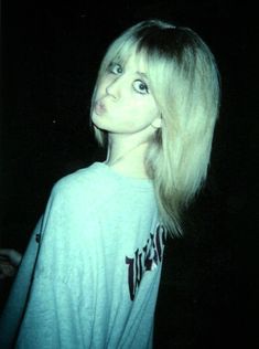 a woman with long blonde hair standing in the dark