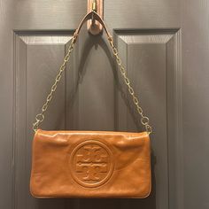 Tory Burch Clutch With Shoulder Strap Beautiful Brown Leather In Good Used Condition. Hardware Light Scratching But Shiney. Leather Is In Good Condition And Shines! Measures 12.5 D X 7 H Tan Clutch Shoulder Bag For Travel, Tan Clutch For Everyday Use, Tan Leather Rectangular Clutch, Tan Bags With Magnetic Closure For Everyday Use, Tan Clutch Bag For Everyday Use, Chic Tan Clutch For Everyday Use, Chic Tan Clutch For Everyday, Tan Leather Clutch Shoulder Bag, Tan Leather Clutch Bag