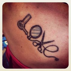 a tattoo with scissors and a magnifying glass on the back of a woman's shoulder