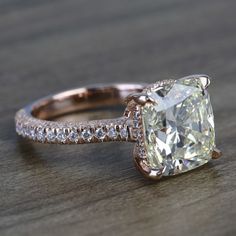 an engagement ring with a cushion cut diamond and pave set diamonds on the sides