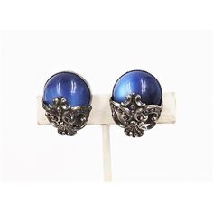 This is part of Chairish’s Costume Jewelry assortment.  1950s Baroque style silvertone blue moonglow clip back earrings. Marked "Napier." Condition: Very good; a normal amount of tarnish for their age. Measure:  1 3/16 inches long by 7/8 inches wide. Identical earrings are shown on pg. 279 of Melinda L. Lewis & Henry Swen's book "The Napier Co.: Defining 20th Century American Costume Jewelry."  Please reference the measurements noted in the description above for the best approximate dimensions. Vintage Nickel-free Earrings For Evening, Nickel-free Vintage Earrings For Evening, Vintage Oval Earrings For Evening, Vintage Metal Cabochon Earrings, Vintage Cabochon Metal Earrings, Vintage Silver Cabochon Earrings, Vintage Silver Earrings With Cabochon, Blue Metal Clip-on Earrings, Vintage Blue Clip-on Jewelry