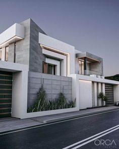 a modern house with two garages on the side of the road in front of an empty street