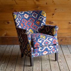 a blue and red chair sitting on top of a wooden floor next to a wall