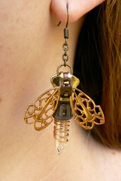 "Fireflies are nature's lantern. Sit long enough at night, and they'll light the way through the dark. That is what we have captured in our steampunk firefly zipper earrings. A zipper body starts this delicate dangle, while natural brass filigree wings are spread to reveal the tiny light (or \"twinklie\", as we like to call it), wound in copper wire. At about 2.25\" from the curve of the ear-wire to the tip of the light, these 1.25\" fireflies are nearly weightless, and will accentuate any style Zipper Earrings, Moda Steampunk, Steampunk Crafts, Steampunk Earrings, Diy Armband, Steam Punk Jewelry, Style Steampunk, Steampunk Diy, Steampunk Accessories