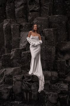 a woman in a white dress standing on rocks