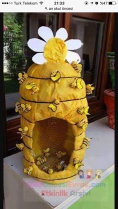 a yellow beehive with flowers and bees on it's roof is shown