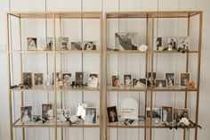 several shelves with pictures and flowers on them in a white walled room filled with wood planks