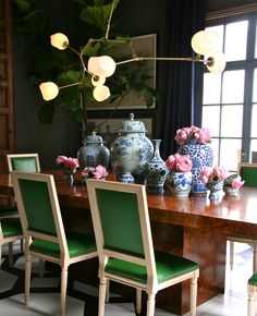 a dining room table with green chairs and vases on it