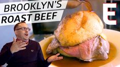 a man standing in front of a roast beef sandwich on a plate with a sign that says brooklyn's roast beef