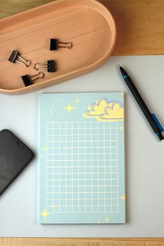 a desk with a pen, cell phone and clipboard attached to the top of it