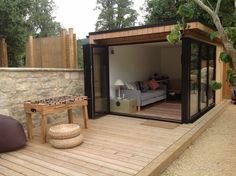 an outdoor living area with a couch, table and chair on the decking outside