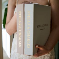 a woman holding a book in her hands and wearing a wedding dress with gold lettering on it