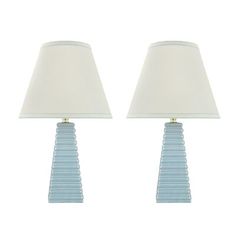 two blue glass lamps sitting next to each other on a white background with one lamp turned off