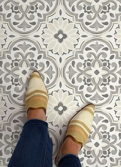 a person with striped socks standing in front of a patterned wallpapered flooring