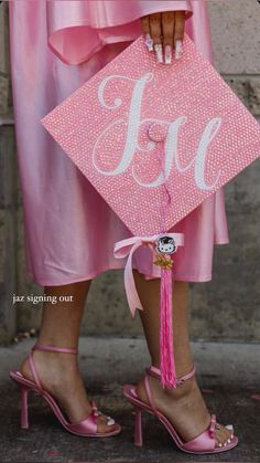 a woman wearing pink high heels holding a pink graduation cap with the word fo on it