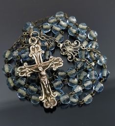 A beautiful vintage French blue rosary with silver crucifix cross, in good condition. Rosary measures approx. 39 cm (15 inch) in length and has nice transparent blue glass faceted beads which are intact and very pretty. The connector is ornate, this interesting rosary would make a nice gift for someone special or a collector. Box on photos is NOT included! A stunning religious jewelry shop well worth a visit ... https://www.etsy.com/shop/100saints. PLEASE LOOK AT THE PICTURES, THEY ARE PART OF T Blue Crucifix Necklace For Spiritual Purposes, Blue Crucifix Necklace For Spiritual Wear, Blue Cross Rosary As Gift, Blue Gemstone Beads Rosary For Spiritual Use, Handmade Blue Rosary With Cross, Handmade Blue Rosary With Cross Shape, Blue Rosary With Round Beads For Gift, Vintage Silver Rosary With Round Beads, Blue Rosary With 8mm Beads In Cross Shape